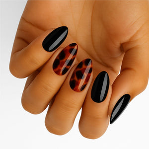 Black glossy and tortoiseshell gel nail wraps on hand showing elegant nail art design