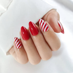 Red and white striped press-on nails on hand with candy cane nail art