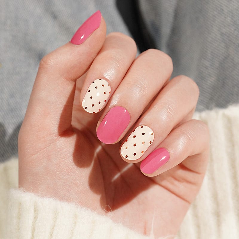 Pink and cream polka dot gel nail wraps on hand showing bonbon pattern manicure
