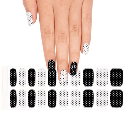 Monochrome polka dot gel nail wraps on hand with matching nail wrap sheet below