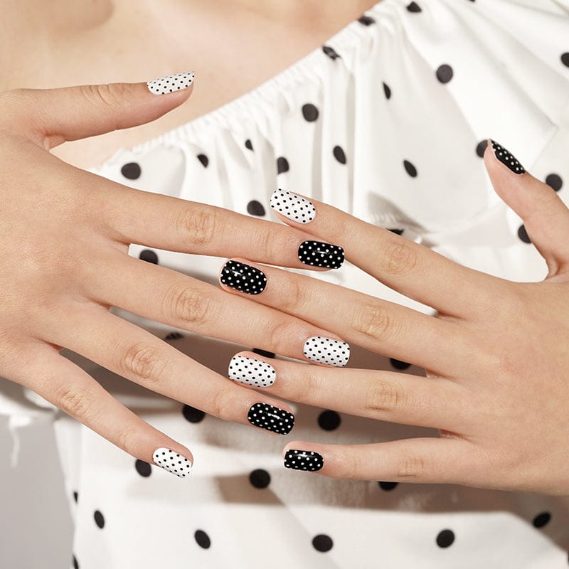 Semi-cured gel nails with alternating black and white polka dot patterns on hands