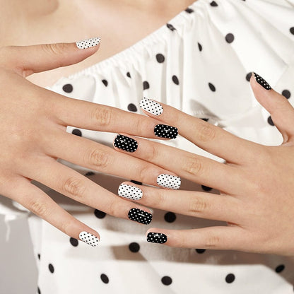 Semi-cured gel nails with alternating black and white polka dot patterns on hands