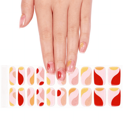 Hand displaying multicoloured gel nail wraps with abstract pink coral gold patterns
