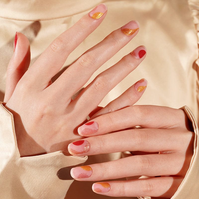 Multiple hands displaying vintage-style gel nail wraps in pink coral gold tones