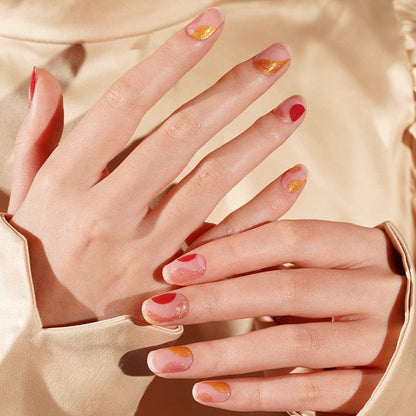 Multiple hands displaying vintage-style gel nail wraps in pink coral gold tones
