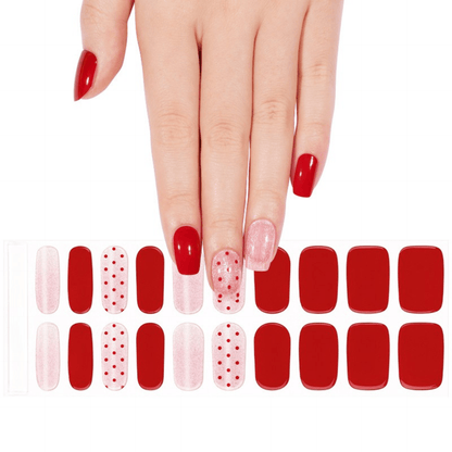 Hand selecting from red and pink dotted gel nail wraps sheet for DIY manicure