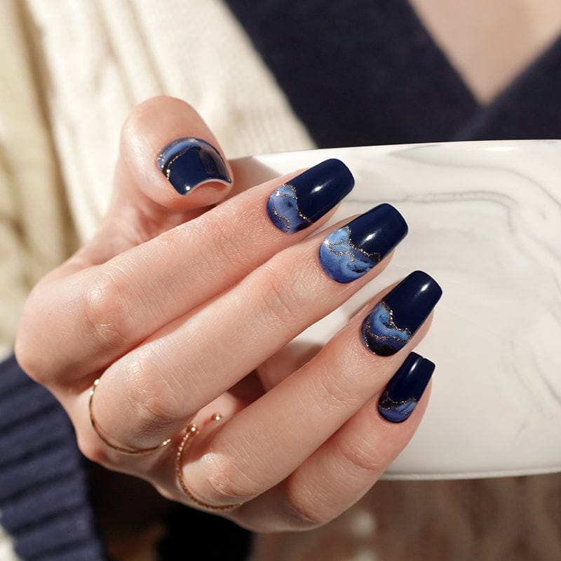 Navy blue ombre gel nail wraps with stormy gradient pattern on hand holding white phone